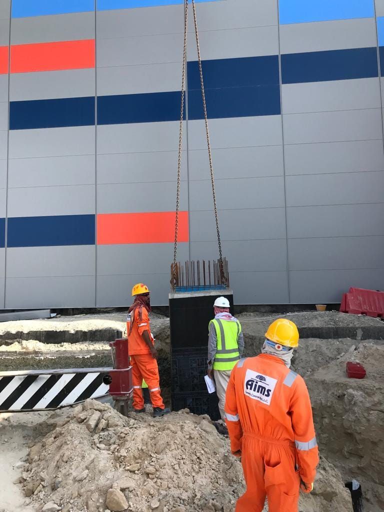 AIMS crew in hard hats and coveralls supervising the placement of a precast chamber